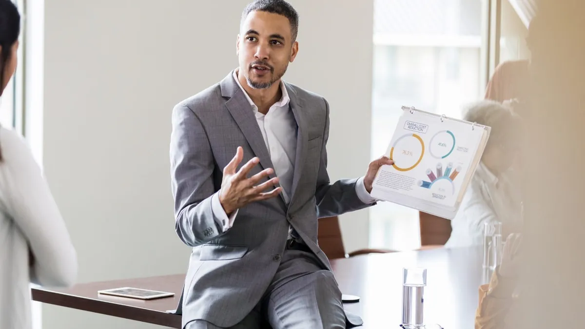 A person in a suit holding a paper

AI-generated content may be incorrect.